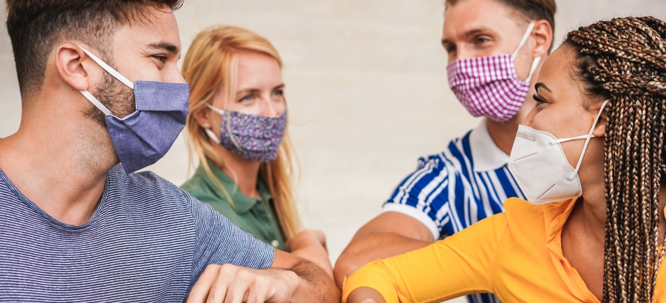 Group of friends bump elbows wearing masks