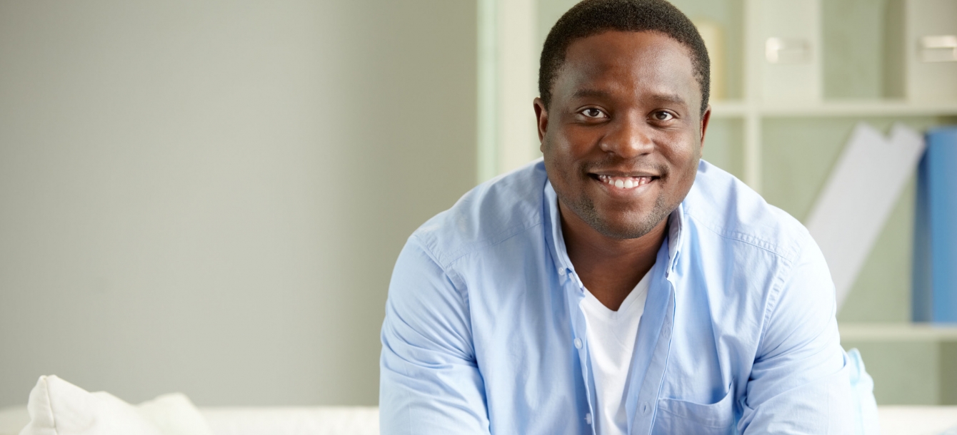 Young man sitting in living room smiling at camera